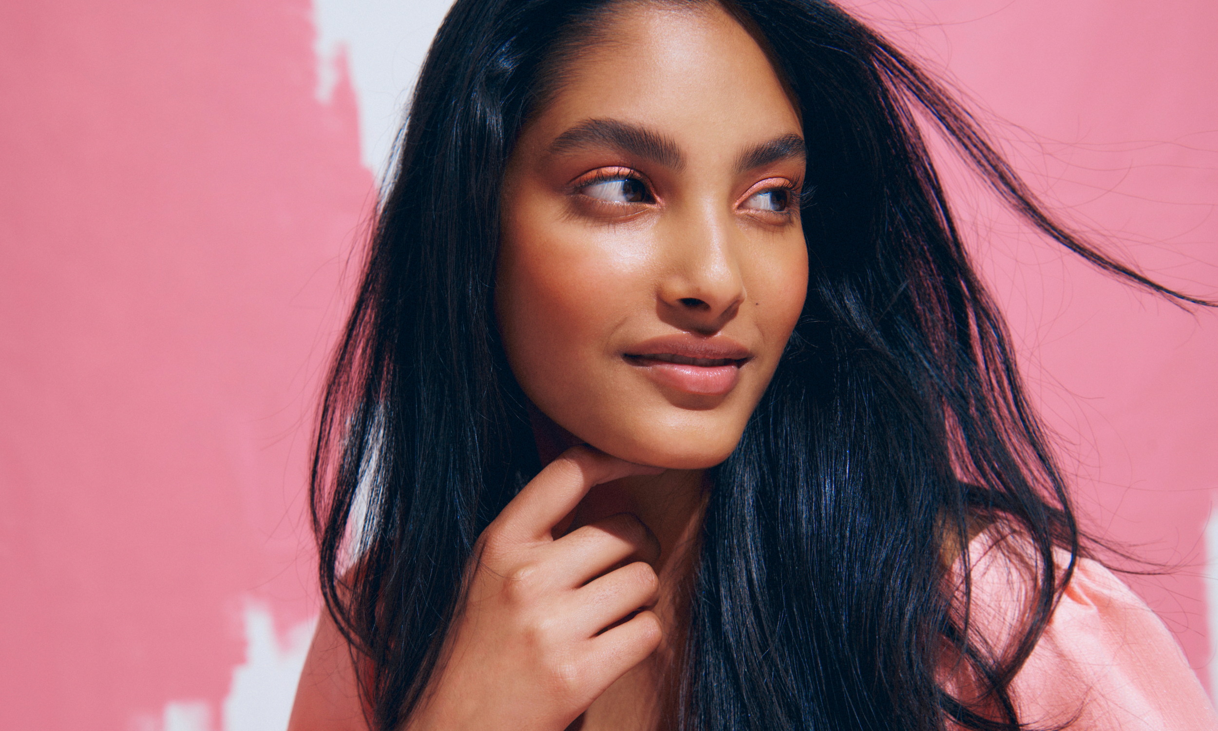 Model wearing Ultra Violette Queen Screen posing in front of a pink background.