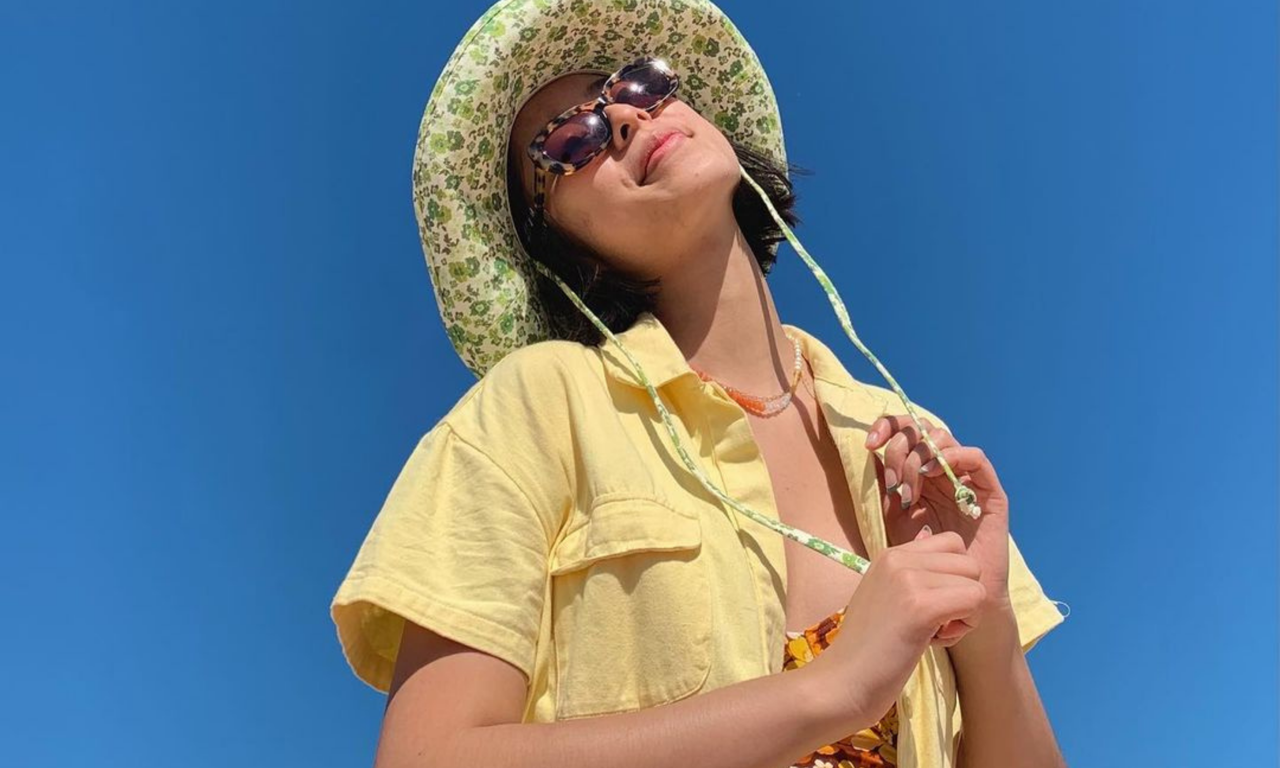 Maggie Zhou wearing Ultra Violette Skinscreen with a yellow top and yellow bucket hat.