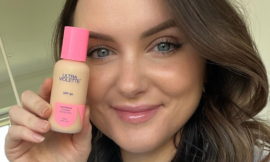 Kate holding a bottle of Ultra Violette Daydream Screen SPF50 Tinted Veil, wearing both Daydream Screen and Supreme Screen.